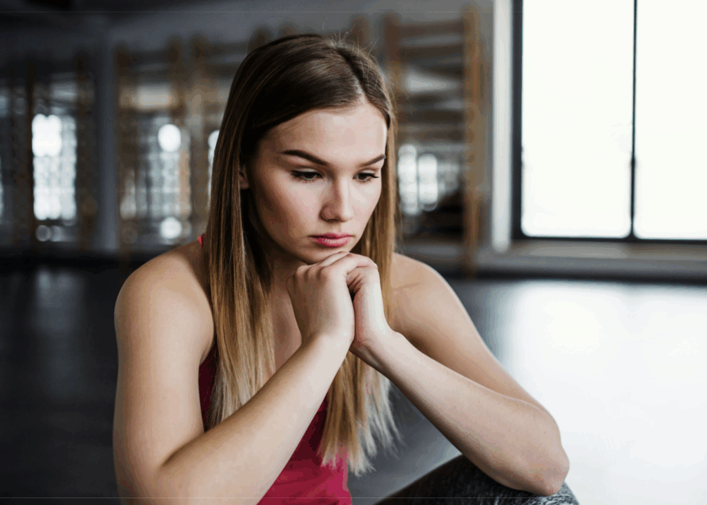 Woman in pink top looking at the ground with her hands folded